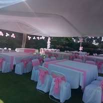 Montaje de evento con mesas y moños rosas